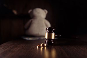 Judge gavel, teddy bear, and wedding rings. Family divorce concept.